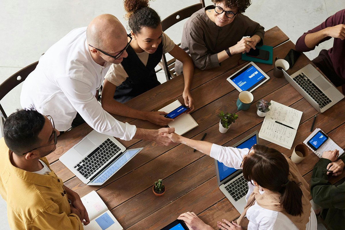 Image of a group of people of different ethnicities at a meeting, with two people shaking hands