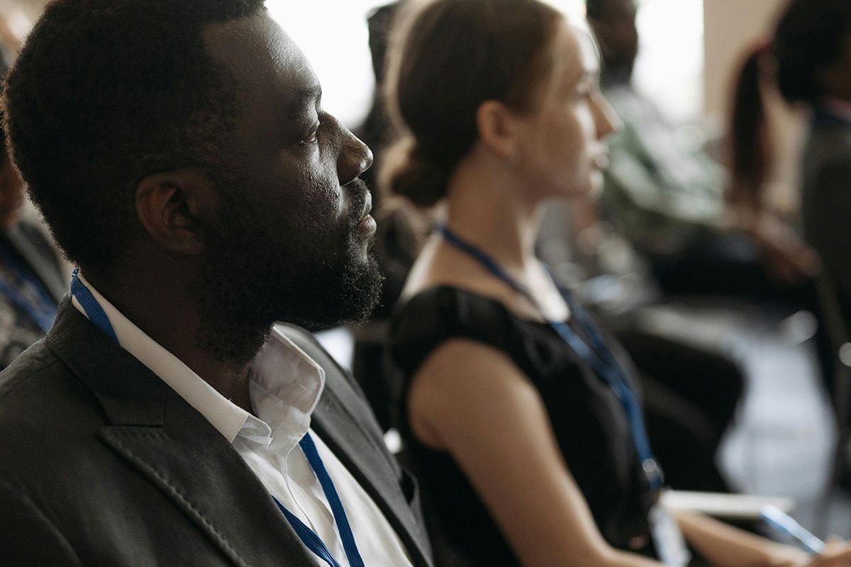 Image of a black man and a white woman in a meeting, with a white man observing